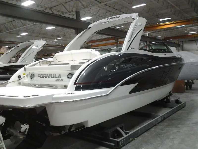 Slide: The Image of 2018 Formula 310 Bowrider boat in showroom, sleek design, white and black exterior. - 5