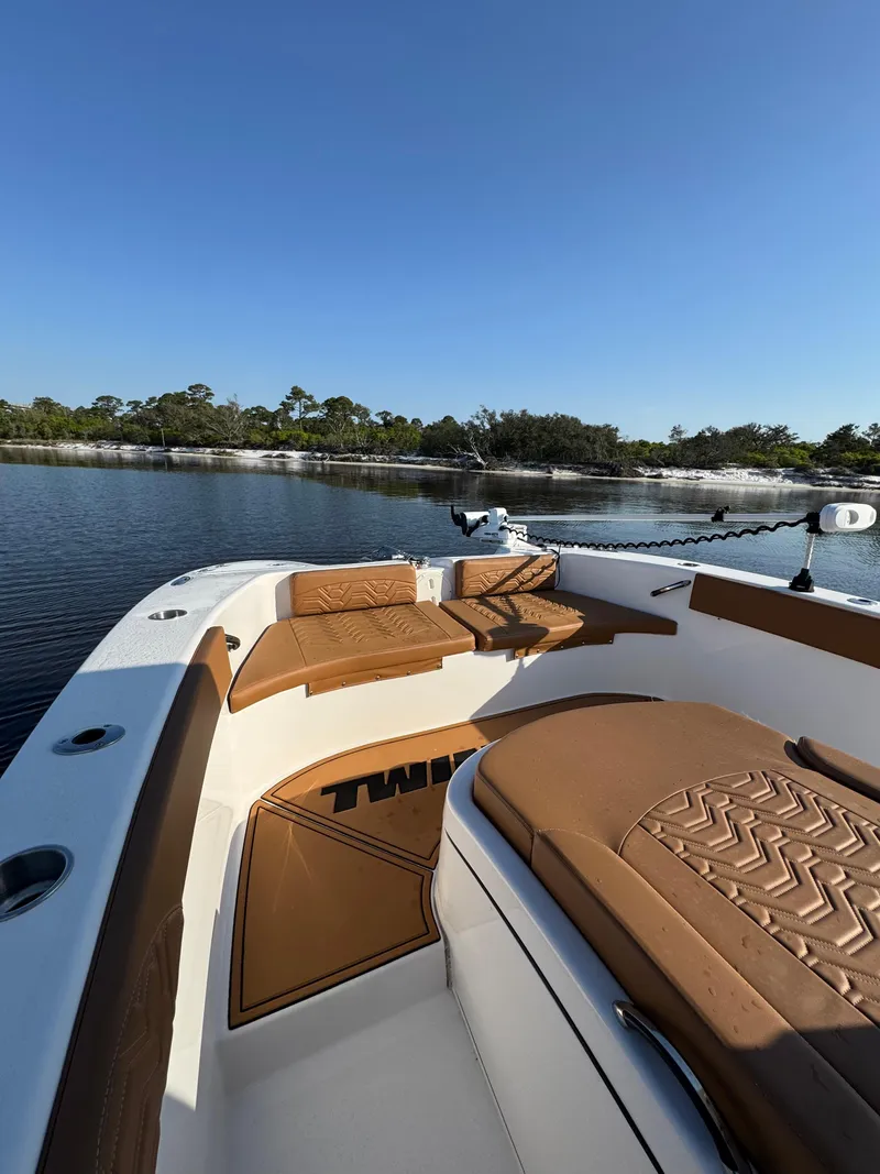 Slide: The Image of 2023 Twin Vee 280 GFX CC boat with brown seating, on calm water under clear blue sky. - 14