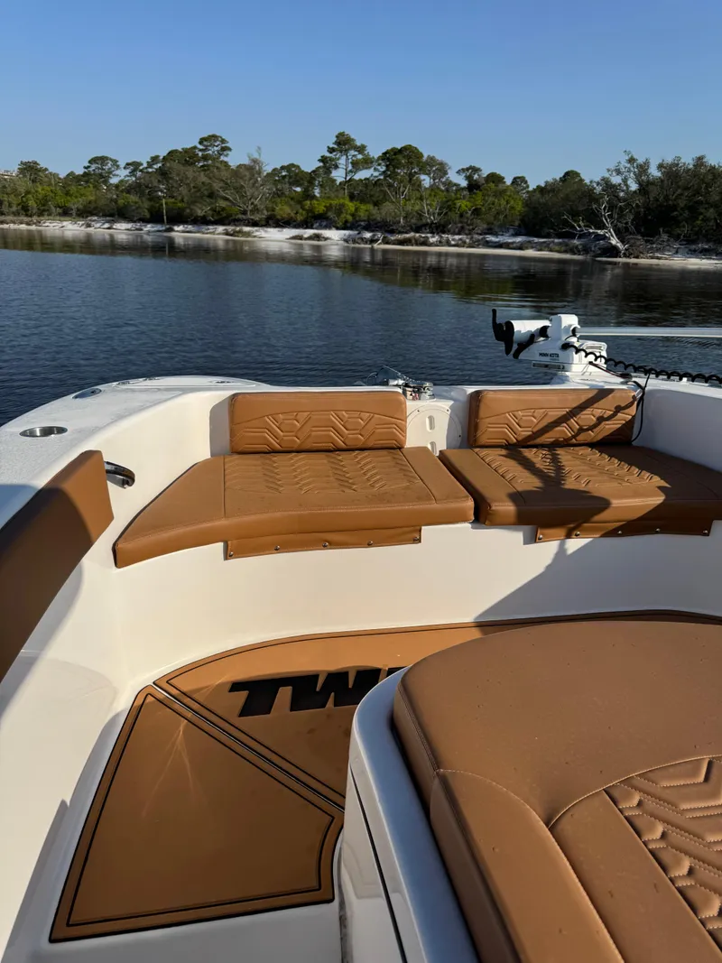 Slide: The Image of 2023 Twin Vee 280 GFX CC boat with tan seating, on calm water, surrounded by trees. - 16
