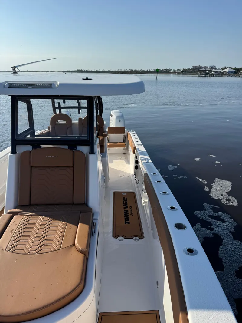 Slide: The Image of 2023 Twin Vee 280 GFX CC boat on calm water, showcasing sleek design and spacious deck. - 18