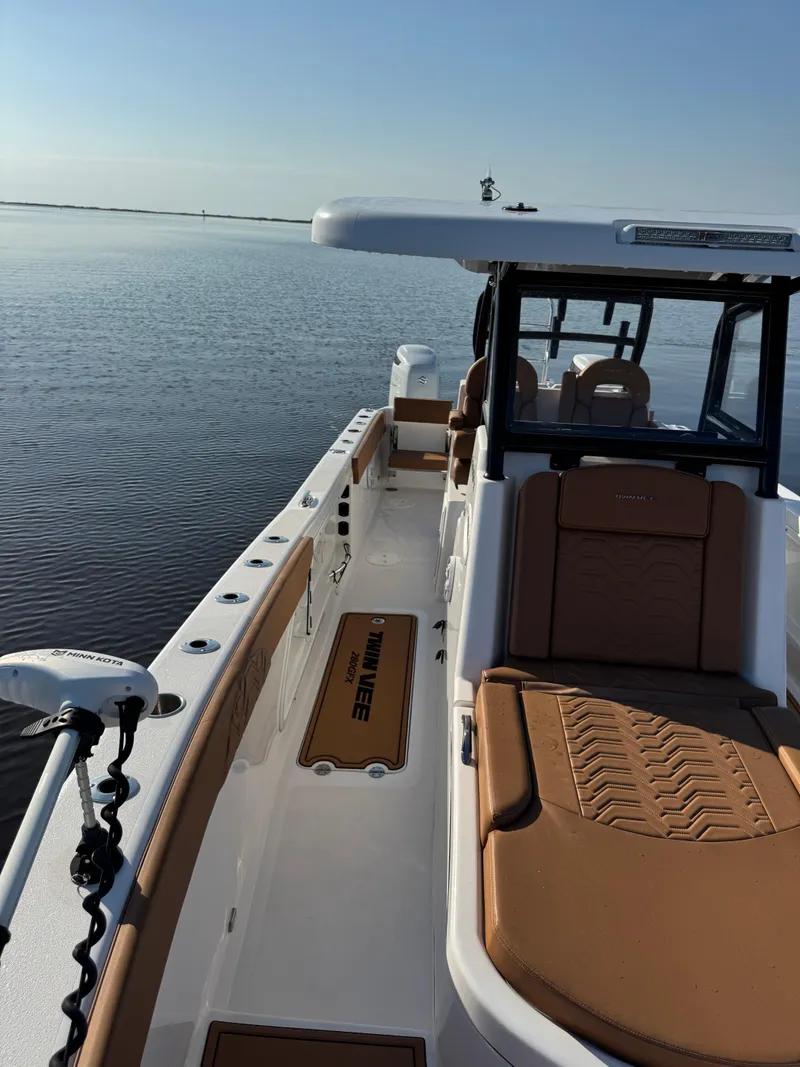 Slide: The Image of 2023 Twin Vee 280 GFX CC boat on calm water, featuring spacious deck and seating. - 19