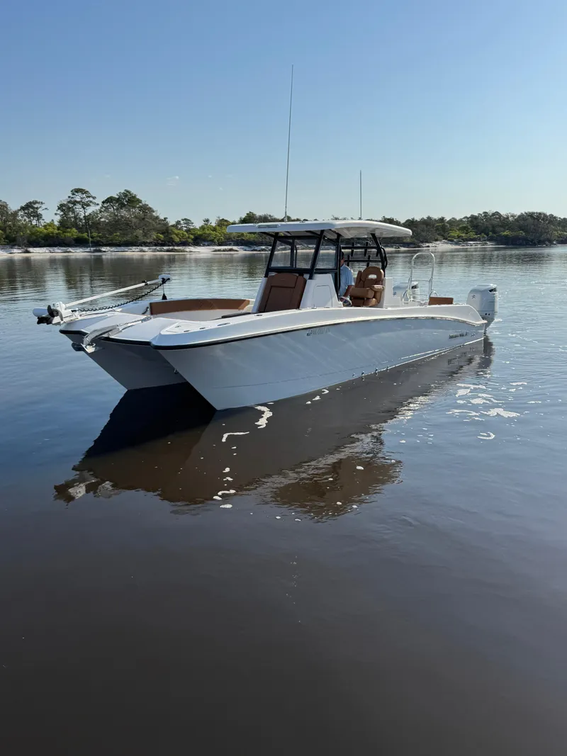Slide: The Image of 2023 Twin Vee 280 GFX CC boat on calm water, clear sky background. - 2