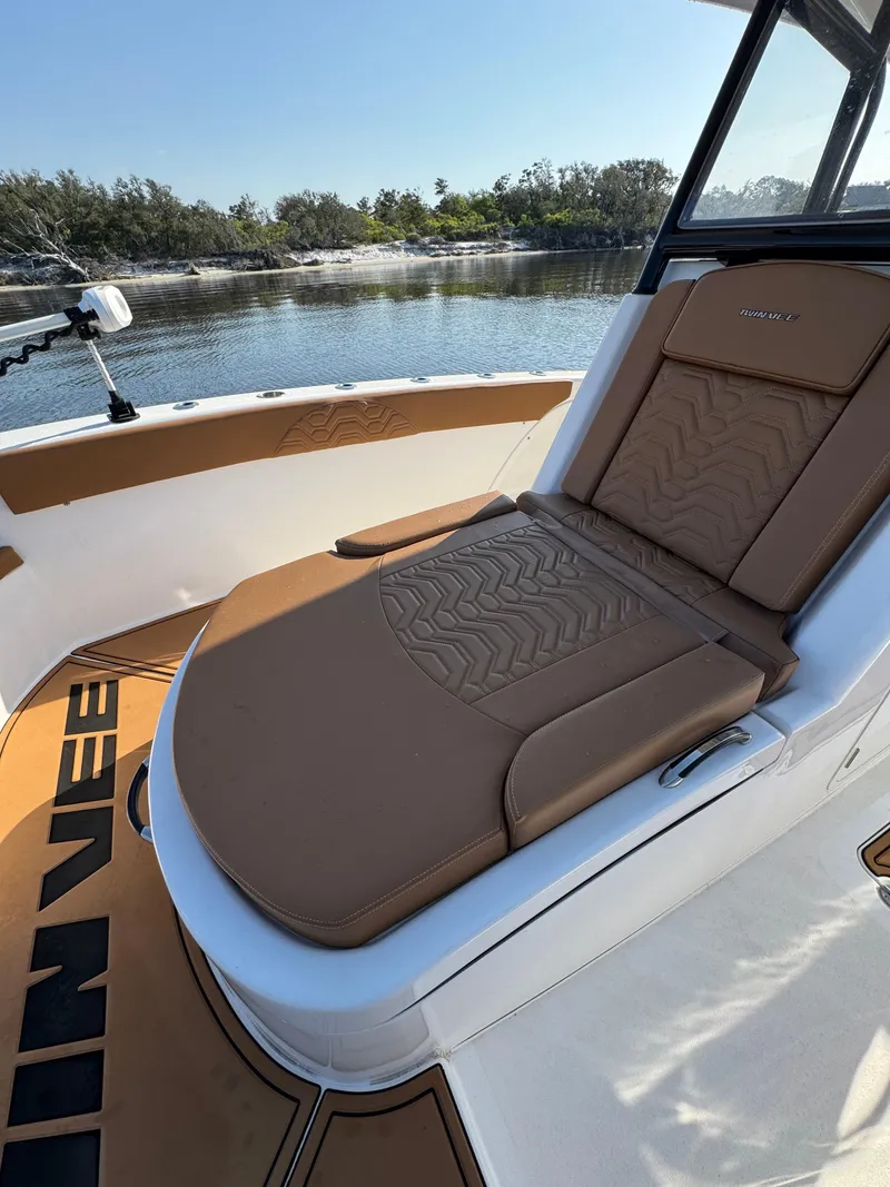 Slide: The Image of 2023 Twin Vee 280 GFX CC boat with brown cushioned seating by the water. - 26