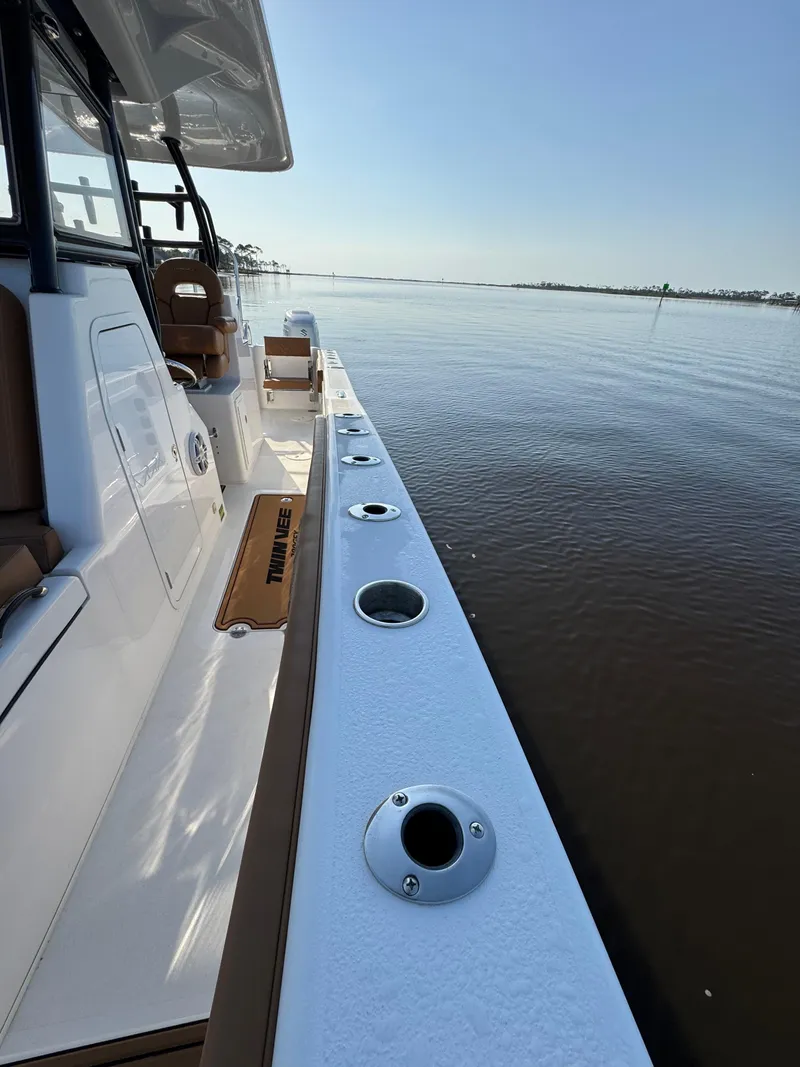 Slide: The Image of 2023 Twin Vee 280 GFX CC boat deck with rod holders, overlooking calm waters. - 28