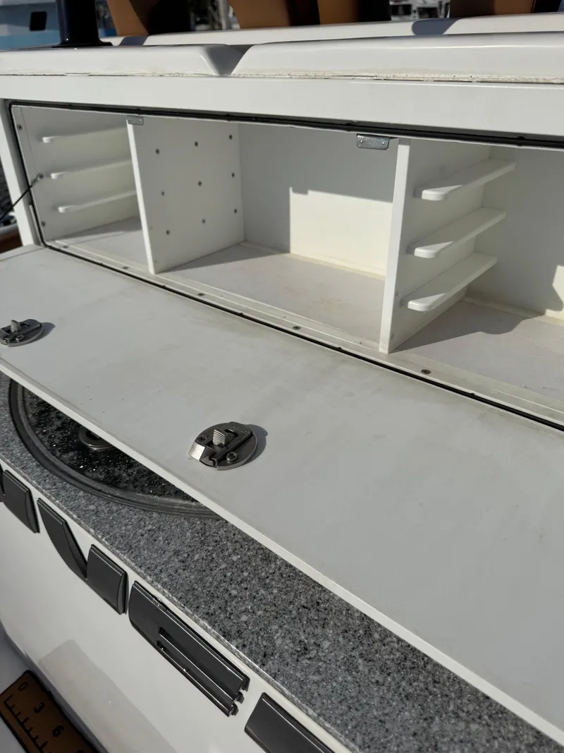 Slide: The Image of 2023 Twin Vee 280 GFX CC boat storage compartment with open shelves and secure latches. - 39