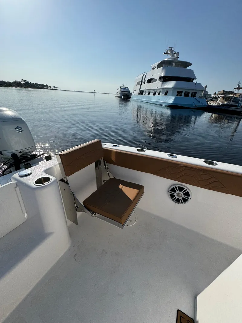 Slide: The Image of 2023 Twin Vee 280 GFX CC boat interior with marina view and luxury yacht in background. - 45
