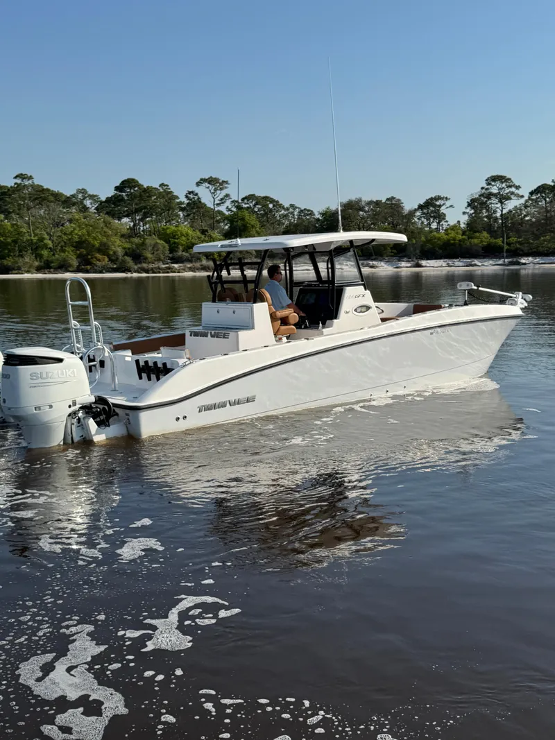 Slide: The Image of 2023 Twin Vee 280 GFX CC boat on calm water, surrounded by trees. - 5