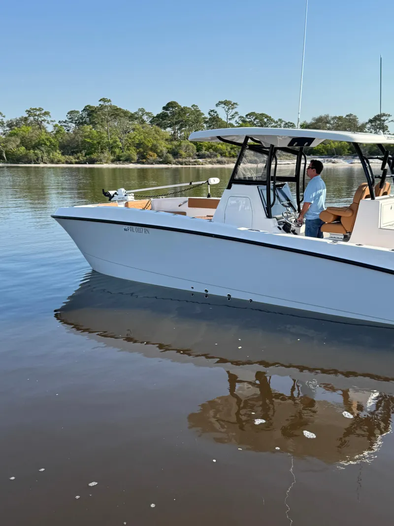 Slide: The Image of 2023 Twin Vee 280 GFX CC boat on calm water with trees in the background. - 8
