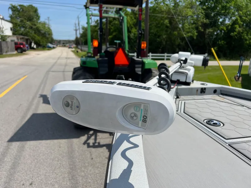 Slide: The Image of 2022 Avid 21 FS boat with trolling motor on a road, tractor in background. - 17