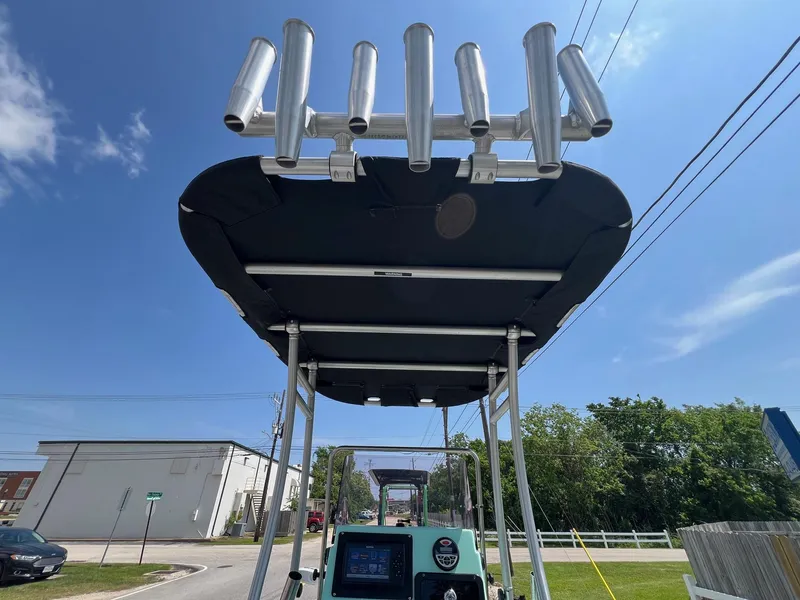 Slide: The Image of Avid 21 FS 2022 boat with rod holders and canopy under a clear blue sky. - 20