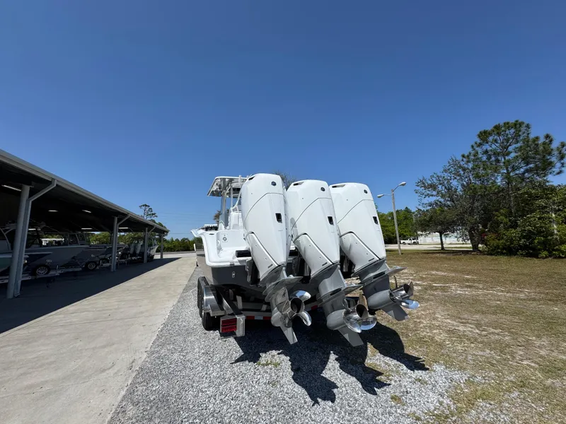 Slide: The Image of 2025 Yellowfin 36 Offshore boat with triple outboard engines, parked outdoors under clear blue sky. - 19