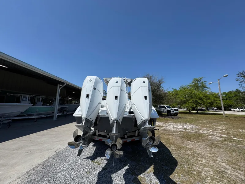 Slide: The Image of 2025 Yellowfin 36 Offshore boat with triple outboard engines, parked outdoors. - 21