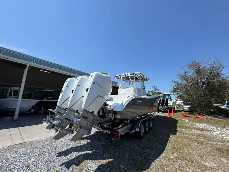 Slide: The Image of 2025 Yellowfin 36 Offshore boat with triple engines on a trailer, parked outdoors. - 22