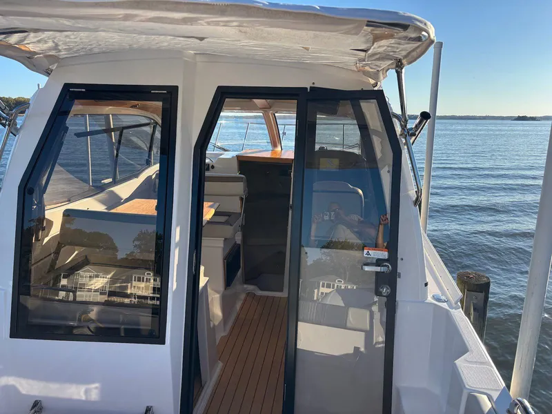 Slide: The Image of 2019 Cutwater C-242 Coupe boat with open cabin doors, docked by the water. - 19