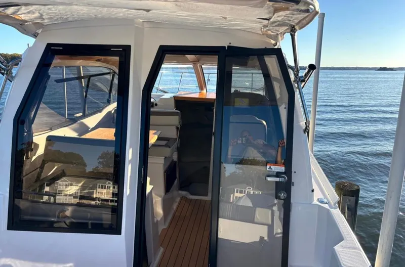Slide: The Image of 2019 Cutwater C-242 Coupe boat with open cabin doors, docked by calm waters. - 2