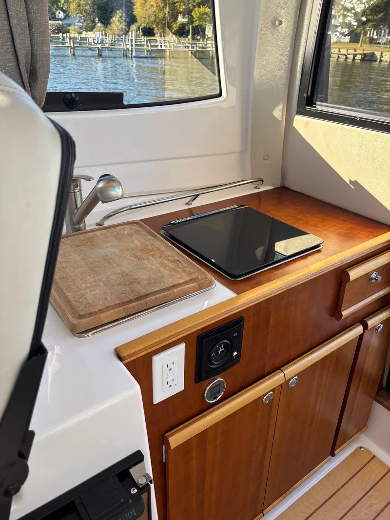 Slide: The Image of 2019 Cutwater C-242 Coupe interior with kitchenette, featuring a stove and cutting board. - 21