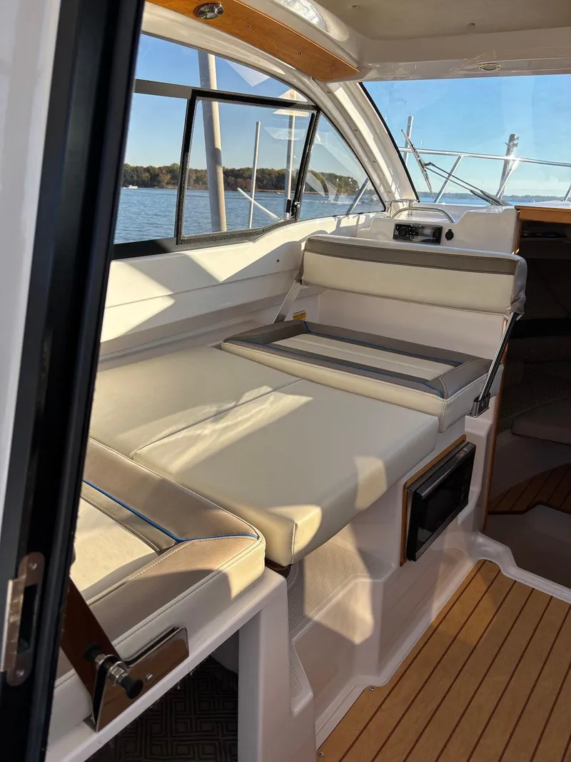 Slide: The Image of 2019 Cutwater C-242 Coupe interior with beige seating and wooden accents, overlooking a serene water view. - 22