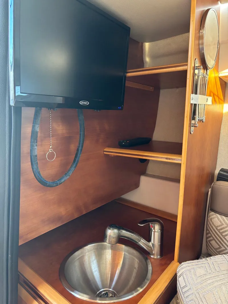 Slide: The Image of 2019 Cutwater C-242 Coupe interior with TV, sink, and wooden shelving. - 24