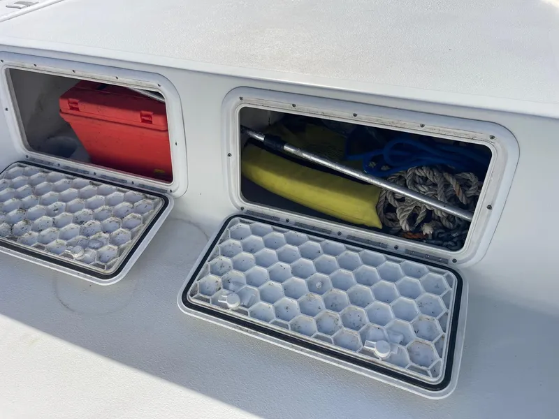 Slide: The Image of Storage compartments on a 2011 Carolina Cat 18CC boat, containing equipment and a red box. - 16