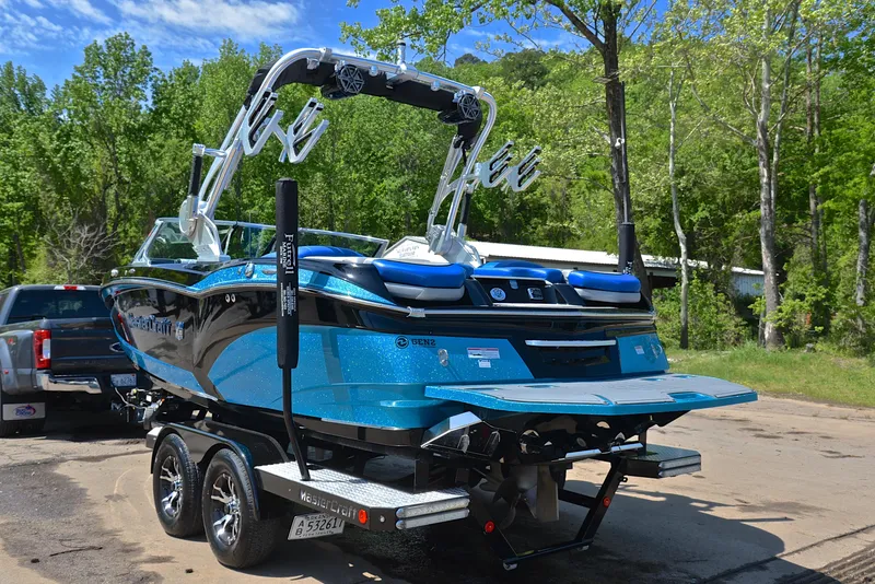 Slide: The Image of 2015 MasterCraft X20 boat on trailer, vibrant blue, parked outdoors with lush greenery. - 12