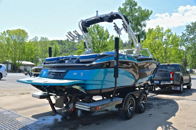 Slide: The Image of 2015 MasterCraft X20 boat on trailer, vibrant blue, parked outdoors. - 14