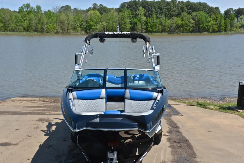 Slide: The Image of 2015 MasterCraft X20 boat on a lakeside ramp, featuring blue and white seating. - 17