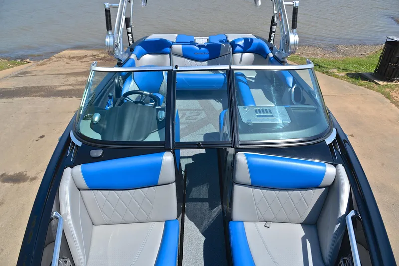 Slide: The Image of 2015 MasterCraft X20 boat with blue and gray interior, docked by the water. - 22