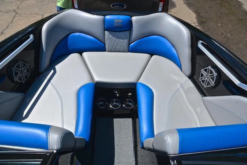 Slide: The Image of 2015 MasterCraft X20 boat interior with blue and gray seating, cup holders, and speakers. - 23
