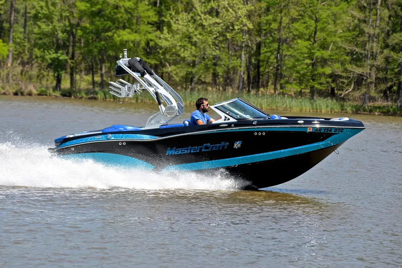 Slide: The Image of 2015 MasterCraft X20 speedboat cruising on a lake with lush green trees in the background. - 3