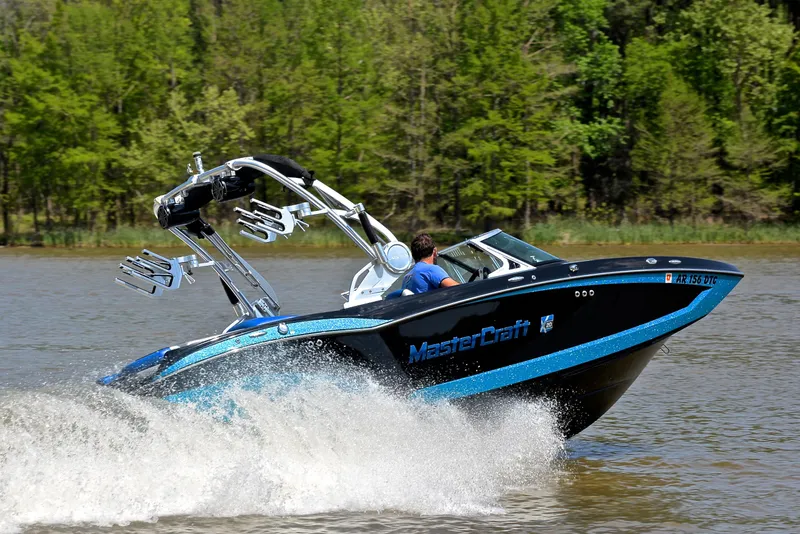 Slide: The Image of 2015 MasterCraft X20 boat cruising on a lake with lush green trees in the background. - 5