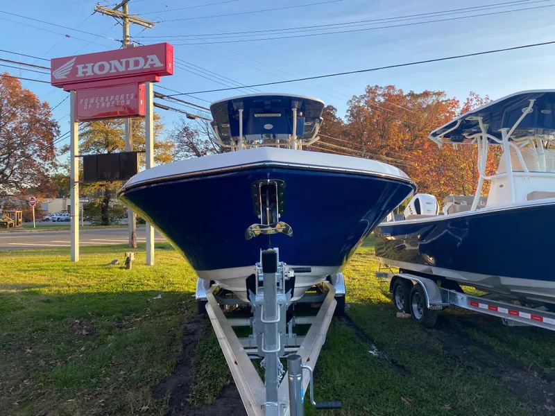 Slide: The Image of 2024 Sea Born LX24 Center Console boat on trailer, displayed outdoors near Honda sign. - 2