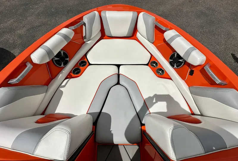 Slide: The Image of 2020 Malibu 21VLX boat interior with orange and white seating, cup holders, and speakers. - 10