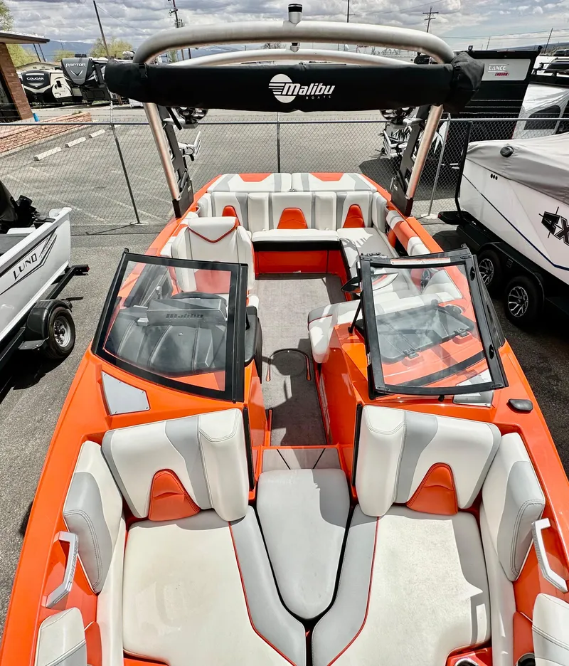 Slide: The Image of 2020 Malibu 21VLX boat with orange and white interior, docked in a marina. - 11