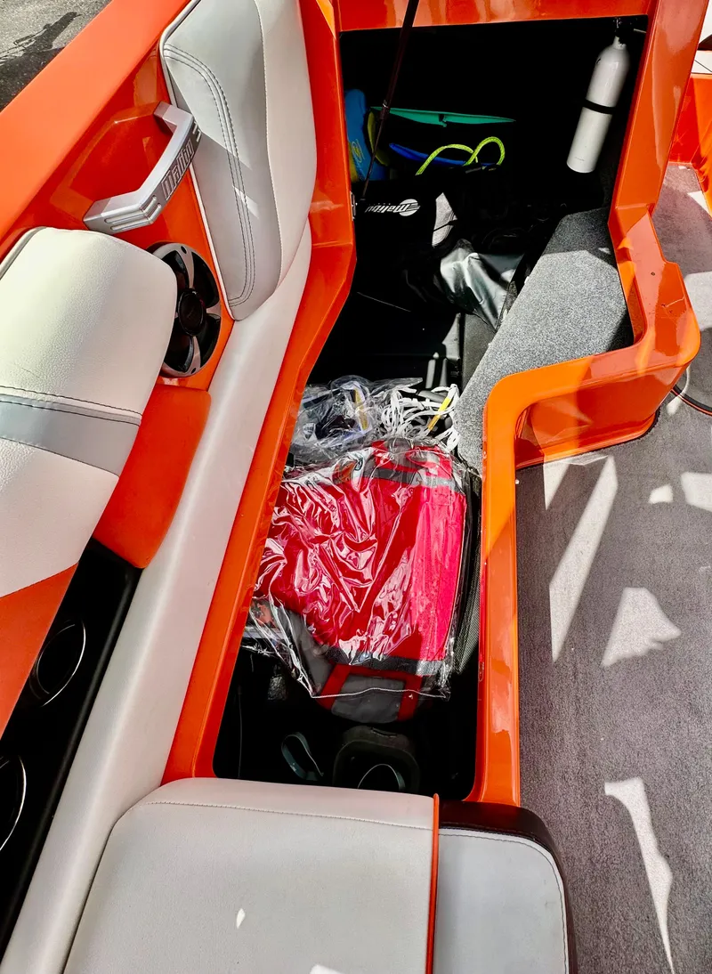 Slide: The Image of 2020 Malibu 21VLX boat interior with orange accents and storage compartment. - 12