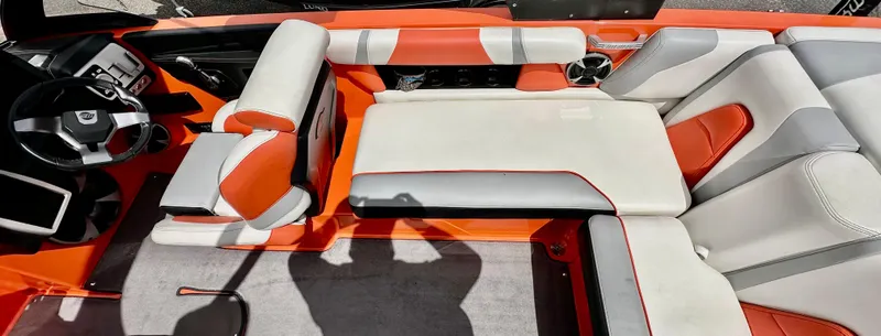 Slide: The Image of 2020 Malibu 21VLX boat interior with orange and white seating, modern dashboard, and spacious layout. - 8