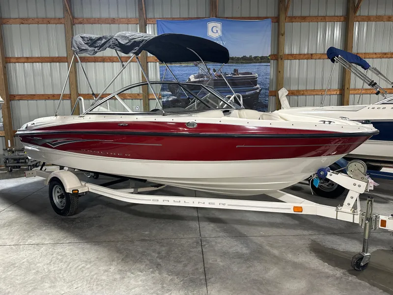 Slide: The Image of 2008 Bayliner 185 boat with red and white exterior on a trailer in a storage facility. - 0