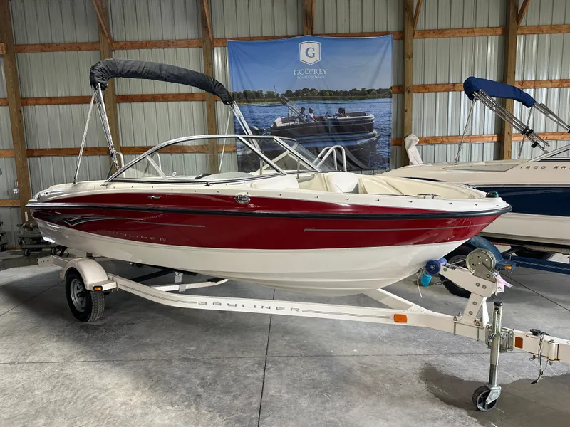 Slide: The Image of 2008 Bayliner 185 boat with red and white exterior on a trailer in a storage facility. - 1