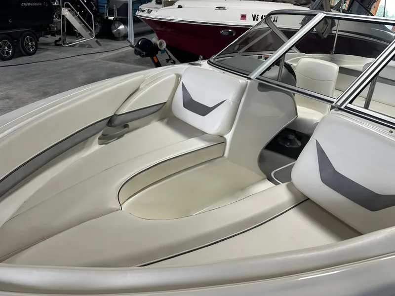 Slide: The Image of 2008 Bayliner 185 boat interior with white seating and windshield in showroom. - 10