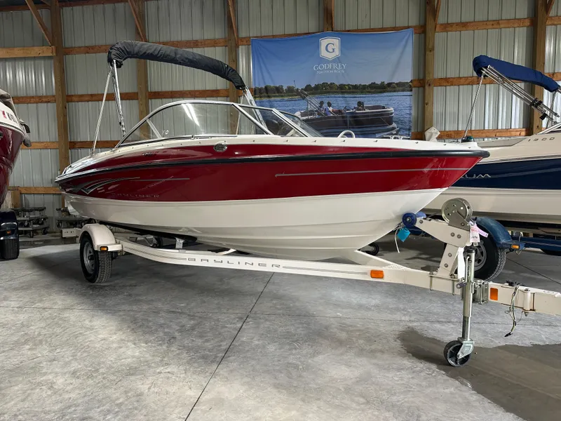 Slide: The Image of 2008 Bayliner 185 boat with red and white exterior on a trailer in a storage facility. - 5