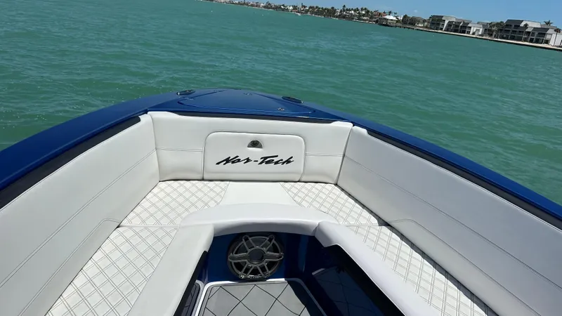 Slide: The Image of 2020 Nor-Tech 390 Sport boat interior with white seating, on calm turquoise water. - 12