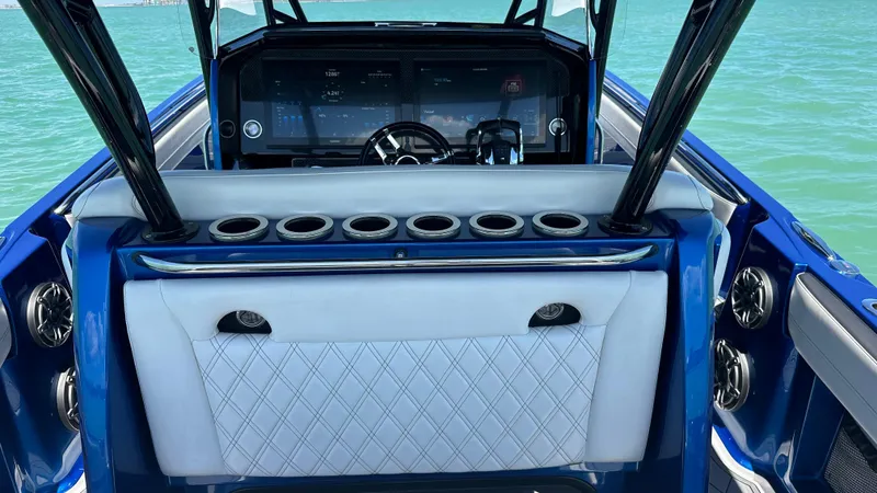 Slide: The Image of 2020 Nor-Tech 390 Sport boat interior with blue and white seating, cup holders, and steering console. - 28