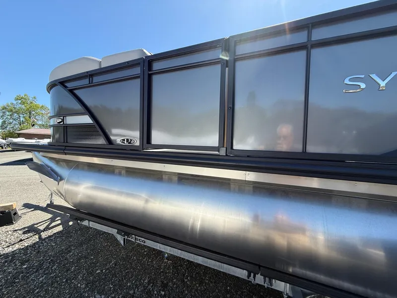 Slide: The Image of 2025 Sylvan L-3 CLZ pontoon boat with sleek metallic finish under bright sunlight. - 2