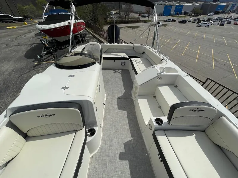 Slide: The Image of 2023 Stingray 212 SC boat with spacious seating and sleek design in a parking lot setting. - 15