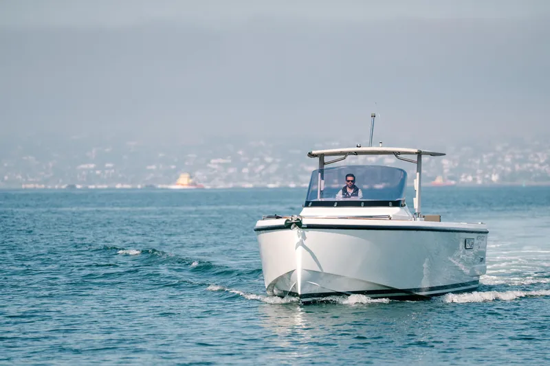 Slide: The Image of 2018 Fjord 36 Xpress boat cruising on calm waters with cityscape in background. - 2