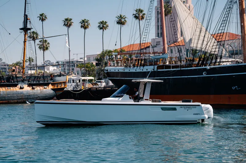 Slide: The Image of 2018 Fjord 36 Xpress boat docked near historic ships and palm trees. - 20