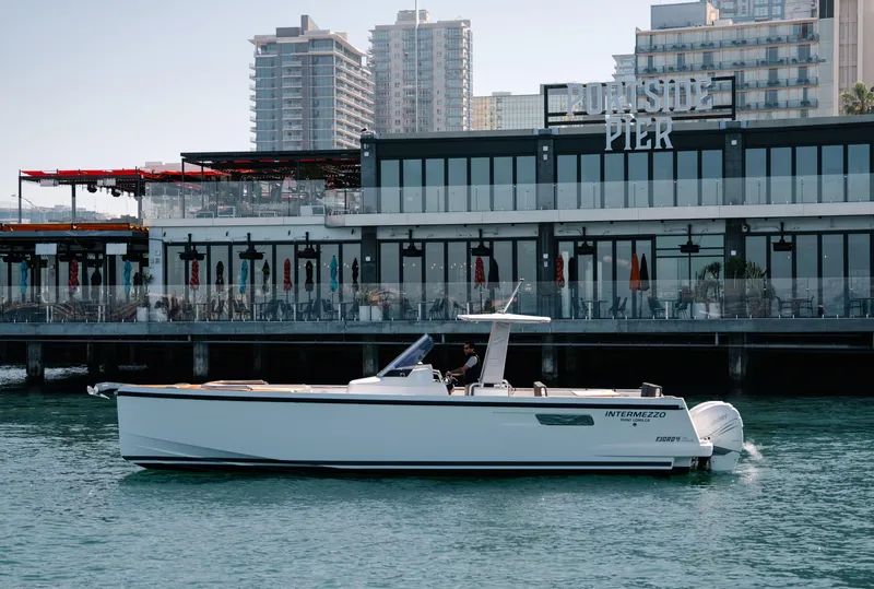 Slide: The Image of 2018 Fjord 36 Xpress boat cruising near a modern pier with cityscape background. - 3