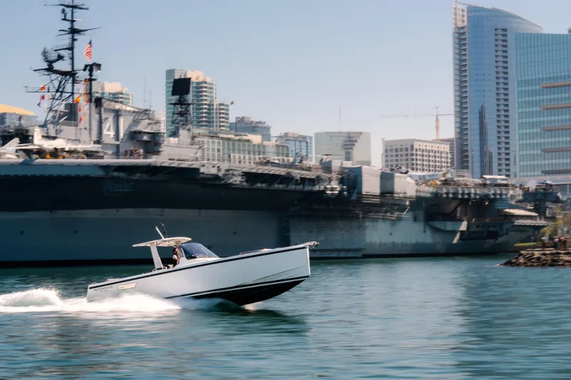 Slide: The Image of 2018 Fjord 36 Xpress cruising near a large battleship in an urban harbor setting. - 6