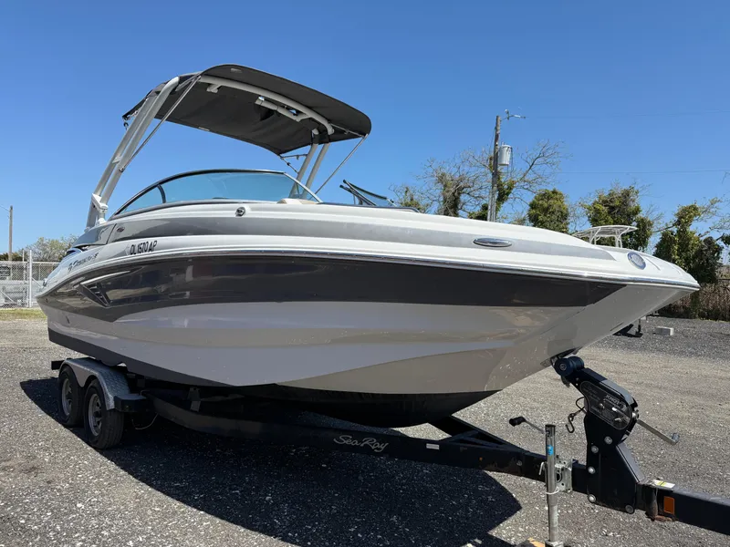 Slide: The Image of 2022 Crownline Eclipse E235 XS boat on trailer, parked outdoors under clear blue sky. - 6