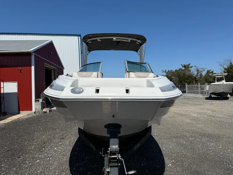 Slide: The Image of 2022 Crownline Eclipse E235 XS boat parked outdoors near a red building. - 7