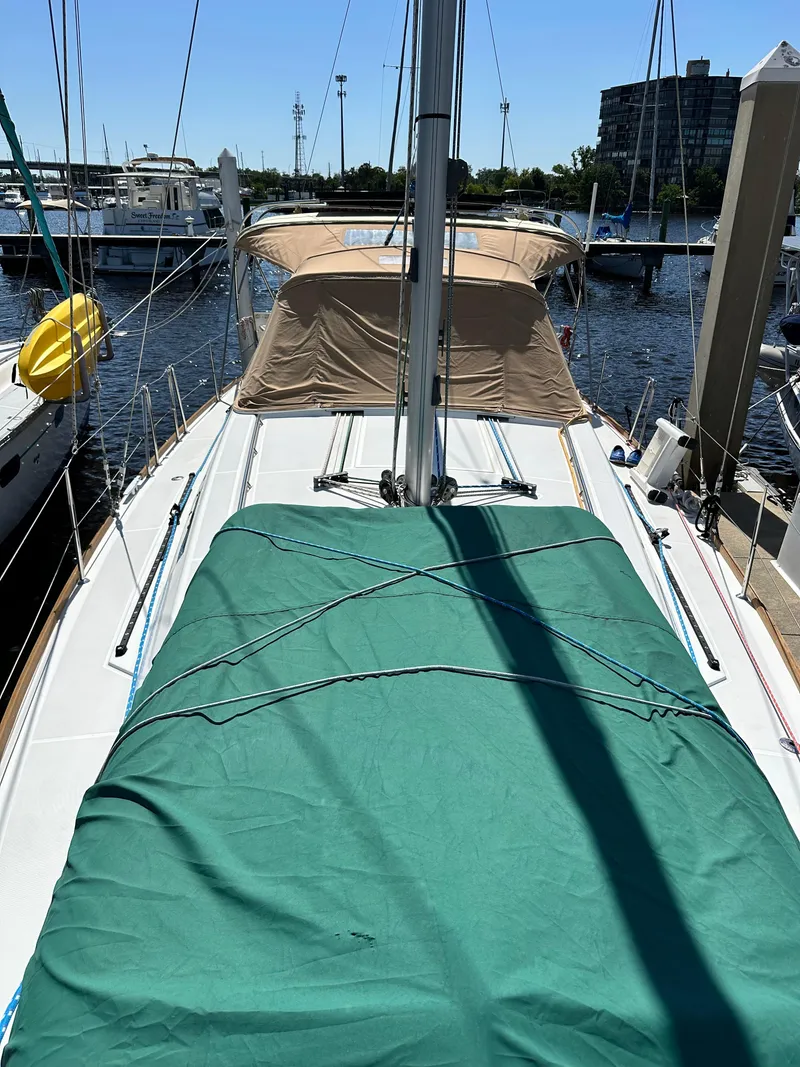 Slide: The Image of 2012 Beneteau Oceanis 41 sailboat docked, featuring a covered deck and mast. - 13